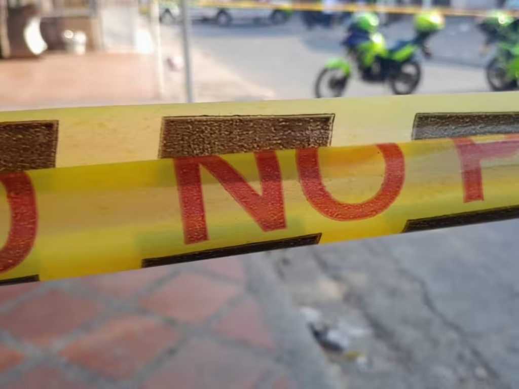 Cinta amarilla de acordonamiento en primer plano y policías en motocicleta al fondo. Robo en Belén Rosales a Esteban Ramírez Parra.