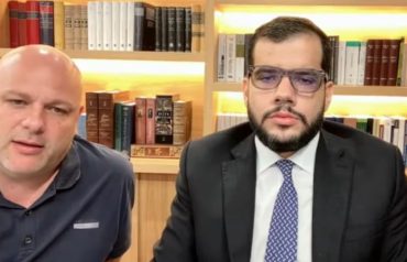 Dos hombres frente a una cámara durante la audiencia virtual de imputación a Miguel Quintero en caso AMVA.