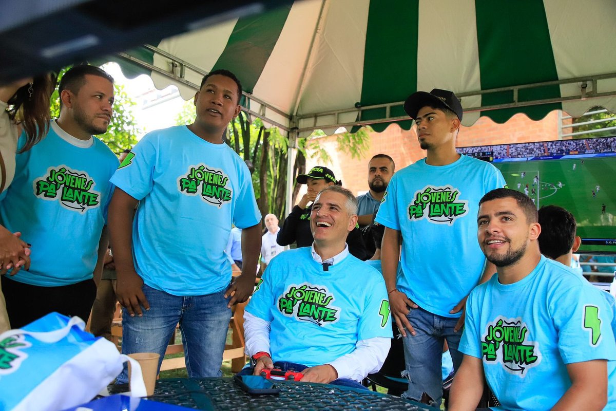 Asistentes con camisetas de Jóvenes Pa’Lante reunidos bajo una carpa frente a una pantalla.