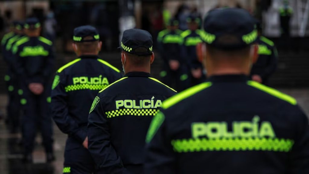 Varios policías de espaldas, con uniformes oscuros e inscripciones amarillas de la Policía. Referencia a explosión en Medellín.