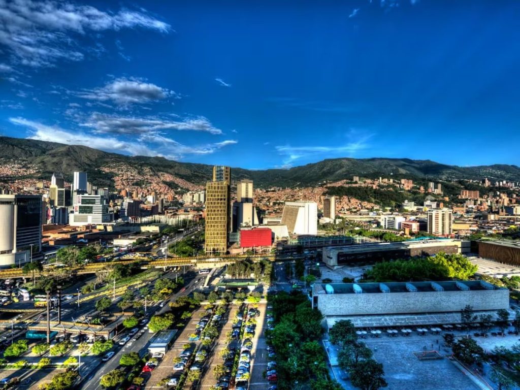 Vista panorámica de Medellín con edificios, vías y montañas bajo un cielo azul. POT de Medellín.
