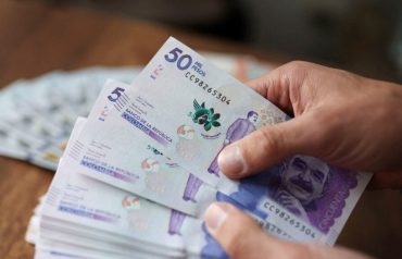 Manos contando billetes colombianos de 50.000 pesos. Referencia a presupuesto 2027.