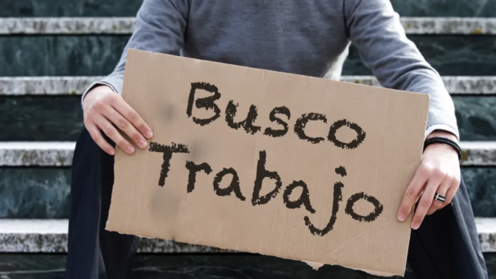 Persona sostiene un cartel que dice «Busco trabajo», ilustración del desempleo en Colombia.