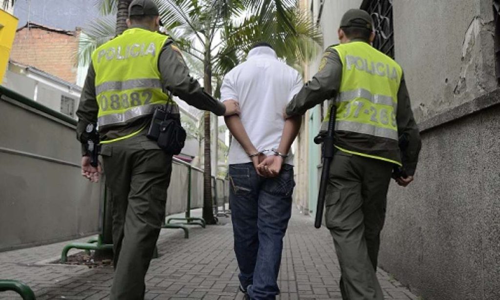 Dos policías acompañan a un hombre esposado, visto de espaldas, durante un procedimiento de captura. No corresponde a la captura de Alias la Liendra.