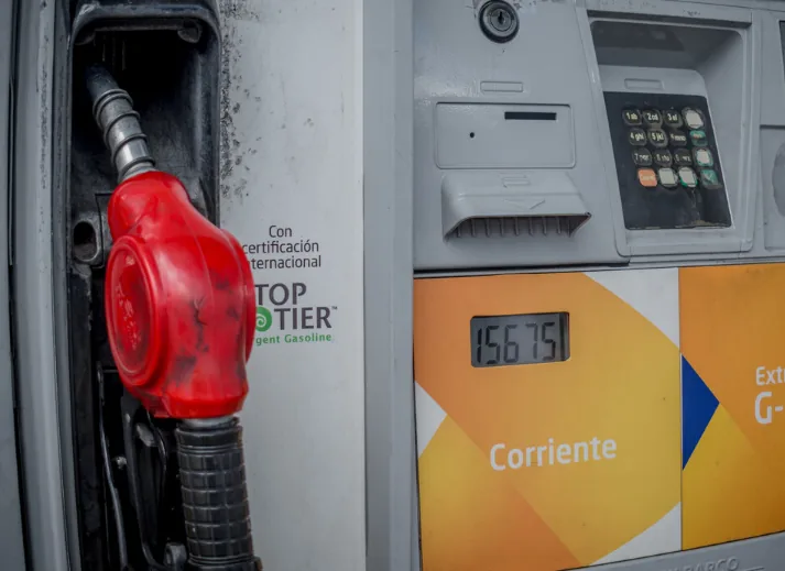 Surtidor de gasolina corriente con boquilla roja y pantalla de precio de la gasolina.
