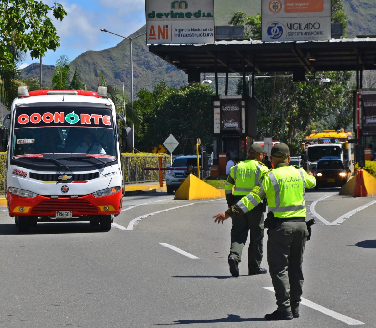 Policías orientan el tránsito junto a un bus en un peaje de las vías de Antioquia.