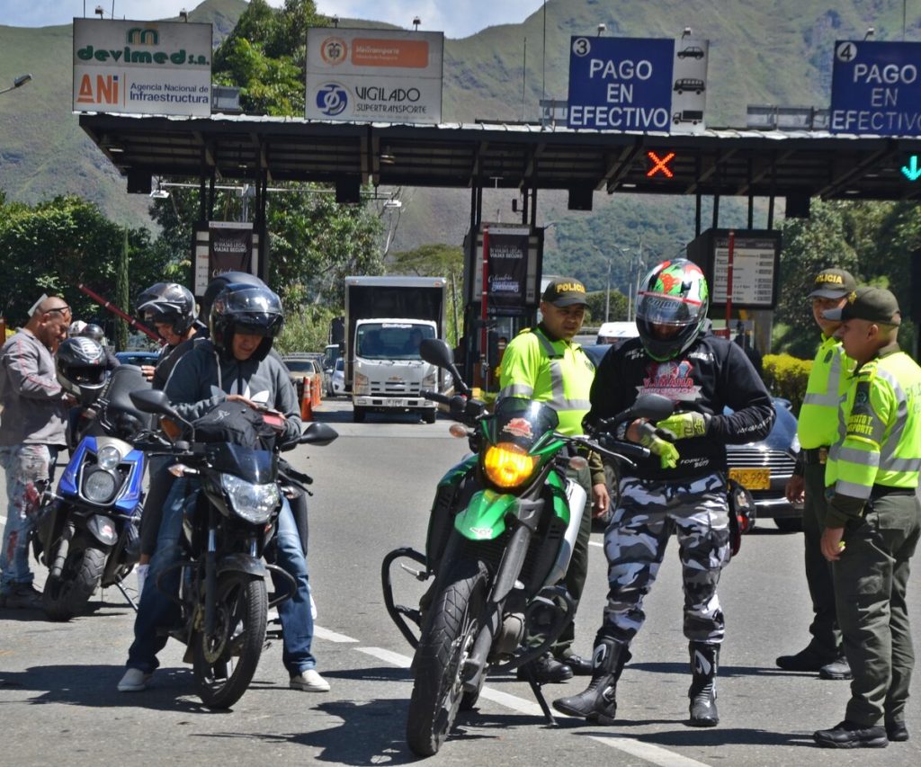 Policías de Tránsito junto a motociclistas en un peaje de las vías de Antioquia.